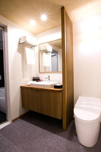 a bathroom with a sink and a toilet and a mirror at Kyoto Kamanza Hotel in Kyoto