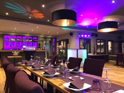 a long table in a restaurant with purple lighting at Boutique Hotel Lindenhof, Bed & Breakfast in Aurich