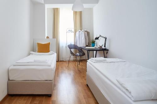 two beds in a room with a desk and a chair at Moodeight Apartments in Skopje
