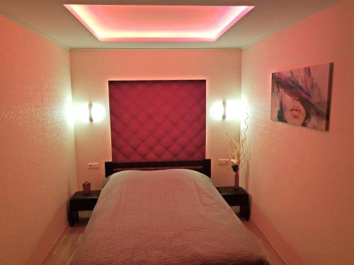 a bedroom with a bed with a red headboard and lights at ApartLux 2 in Chernihiv