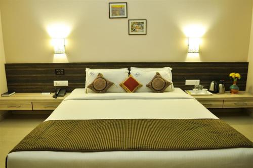 a bedroom with a large bed with two tables and two lamps at Hotel K Square in Kolhapur
