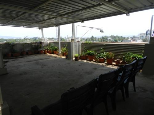 a patio with chairs and potted plants on a roof at Hotel K Square in Kolhapur