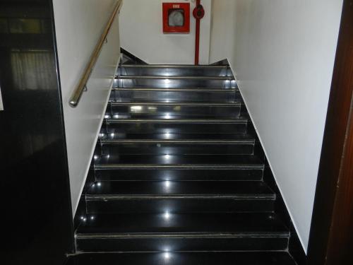 a staircase with black steps with a clock on the wall at Hotel K Square in Kolhapur
