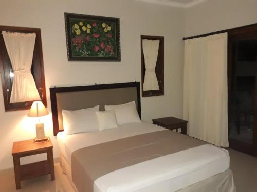 Un dormitorio con una gran cama blanca y una ventana en Dewa Put Guest House en Ubud