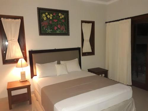 a bedroom with a large white bed and a window at Dewa Put Guest House in Ubud