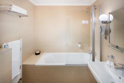 a white bath tub sitting next to a white sink at Boutique Hotel Seven Days in Prague