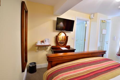a bedroom with a bed with a mirror and a tv at The Talbot Hotel in Cleobury Mortimer
