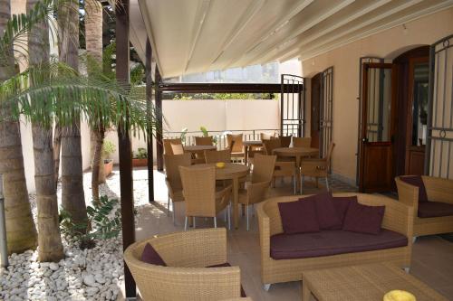 une terrasse avec une table, des chaises et des arbres dans l'établissement Hotel Il Portico, à Favignana