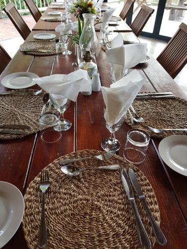 a long wooden table with plates and utensils on it at Avoca River Cabins in Addo