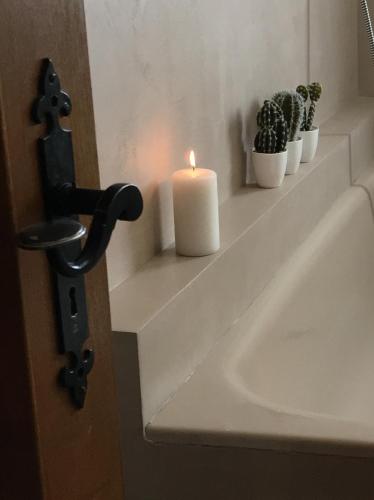 une bougie sur une étagère à côté d'un évier dans l'établissement La Maison Bleue, à Kientzheim