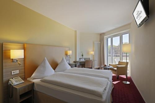 a hotel room with a bed with a phone on it at Parkhotel CUP VITALIS in Bad Kissingen