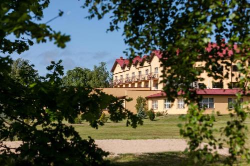 ein großes Haus auf einem Feld mit Bäumen in der Unterkunft BURSZTYN - BERNSTEIN SPA & Wellness in Dąbki