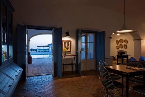a living room with a table and chairs and an open door at Herdade Do Touril in Zambujeira do Mar