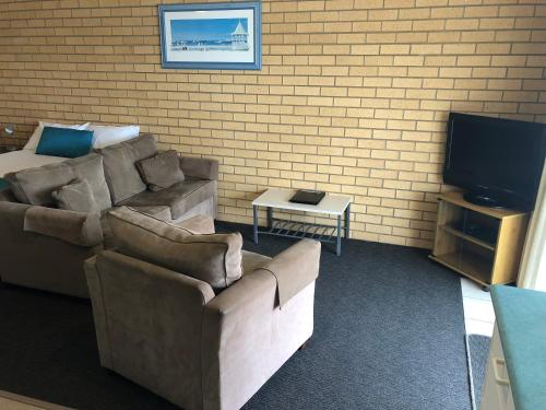 a living room with a couch and a tv at Port Campbell Parkview Motel & Apartments in Port Campbell