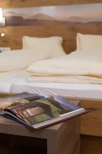 a book on a table next to two beds at Zum Fally - Landgasthof in Kirchberg am Wechsel