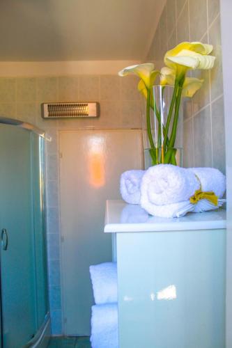 a bathroom with towels and a vase with yellow flowers at Apartments Kut in Vis