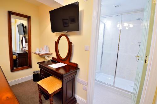 a bathroom with a mirror and a sink and a shower at The George Hotel in Crewkerne