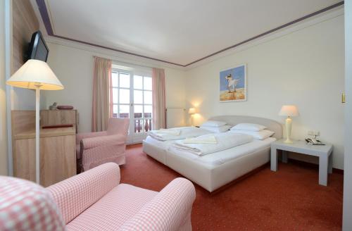 a hotel room with a bed and two chairs at Lust und Laune Hotel am Wörthersee in Pörtschach am Wörthersee