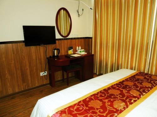a bedroom with a bed and a desk with a television at GreenTree Inn Henan Zhengzhou Chengnan Road Bojue Business Hotel in Zhengzhou