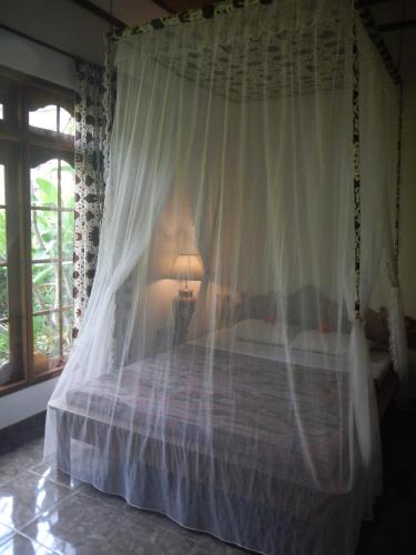 a bedroom with a canopy bed with a lamp at Villa Campi Sorga in Senggigi 