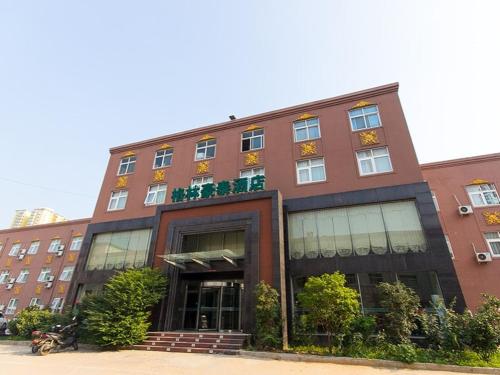a large brick building with windows and plants at GreenTree Inn Henan Zhengzhou Chengnan Road Bojue Business Hotel in Zhengzhou