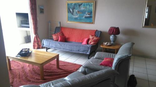 a living room with two couches and a table at La Palma Villas in Mossel Bay