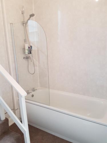 a white bath tub with a shower in a bathroom at AA Apartment Westoe Road in South Shields