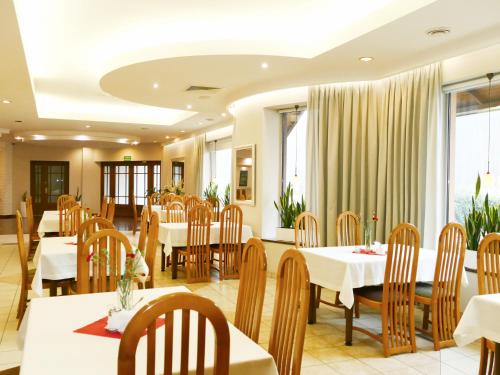 un ristorante con tavoli e sedie bianchi e finestre di Eden a Rydzyna