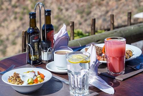 Grootberg Lodge في دامارالاند: طاولة خشبية مليئة بالأطباق الغذائية والمشروبات