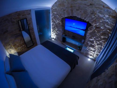 1 dormitorio con 1 cama y TV en una pared de piedra. en Levante Luxury Room, en Giovinazzo