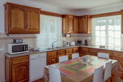 a kitchen with wooden cabinets and a table and a microwave at Casa do Norte (AL) in Biscoitos
