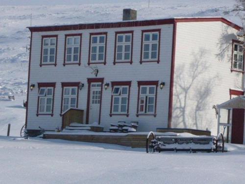 a large white house with snow in front of it at Guesthouse Storu-Laugar in Laugar