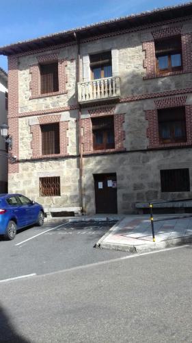 una macchina blu parcheggiata di fronte a un edificio di mattoni di Casa Rural del Río Tejos a El Hornillo