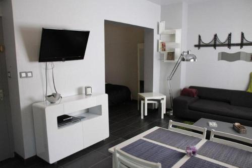 a living room with a couch and a tv on a wall at Appartement Les Confidences in Le Touquet-Paris-Plage