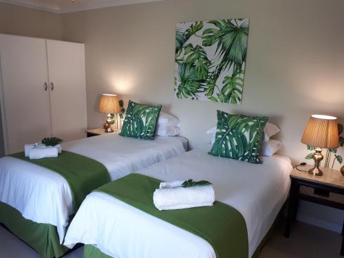 two beds with green and white sheets in a room at Stroke-One-Inn in Umkomaas