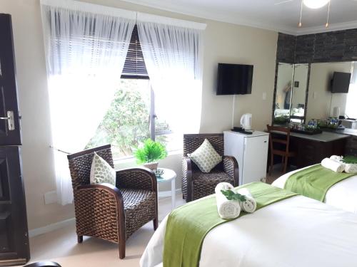 a hotel room with two beds and chairs and a window at Stroke-One-Inn in Umkomaas