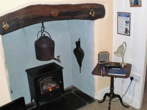a room with a stove and a table with a bird on the wall at Church Lane Cottage in Llanidloes