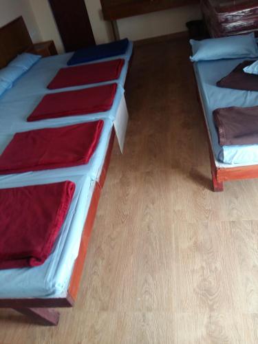 two beds in a room with wooden floors at Nook Residency in Ooty