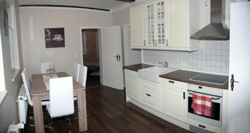 リューネブルクにあるFachwerkhaus in der Altstadtの白いキャビネットと木製のテーブルのあるキッチン