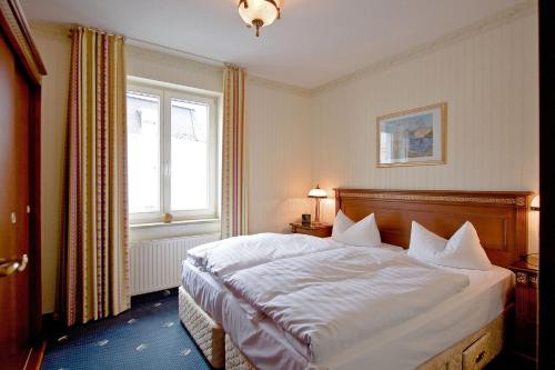 a bedroom with a bed with white sheets and a window at SEETELHOTEL Ostseeresidenz Ahlbeck in Ahlbeck