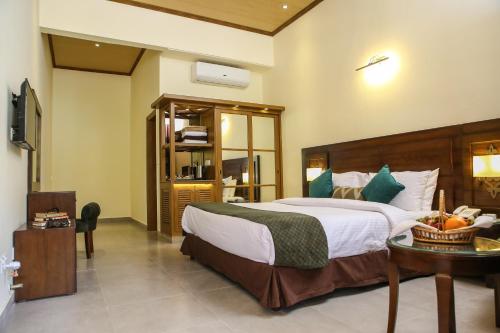 a bedroom with a large bed and a table with a bowl of fruit at Dreamworld Resort, Hotel & Golf Course in Karachi