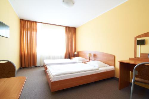 a hotel room with two beds and a desk at Obiekt Hotelarski Patron in Warsaw