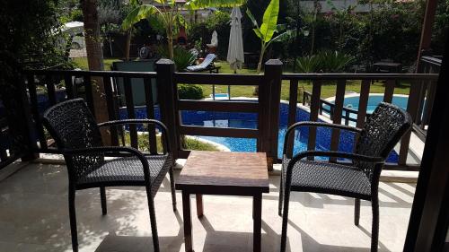 two chairs and a table on a patio with a pool at Alya Hotel Göcek in Göcek