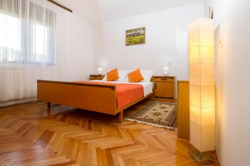 a bedroom with a bed with orange sheets and a wooden floor at Apartman Karlo in Otočac