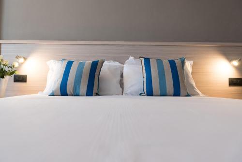 a white bed with blue and white pillows on it at Hotel Lis in Asti