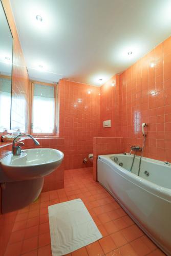 a bathroom with a tub and a sink at Hotel Lis in Asti