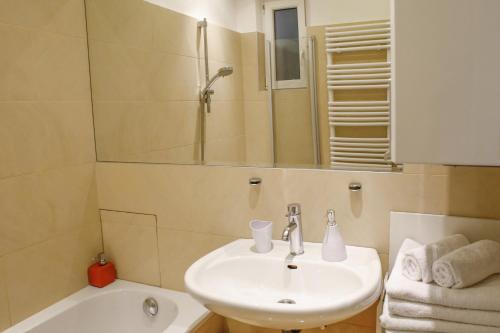a bathroom with a sink and a mirror and a tub at Prestige Vienna Apartment in Vienna