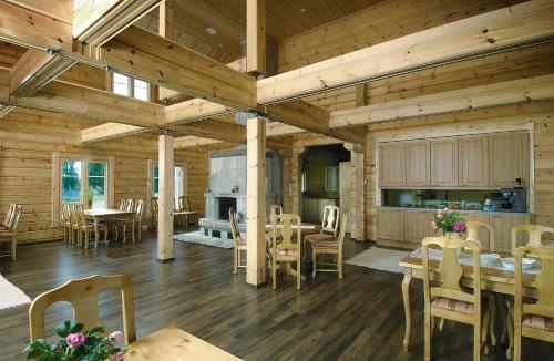 Habitación grande con mesas y sillas en una cabaña de madera. en Guest House Haapaniemen Hirsikartano, en Iisalmi