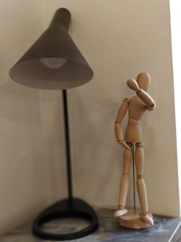 a wooden doll standing next to a lamp with a person looking up at Casa Messi in Pitigliano