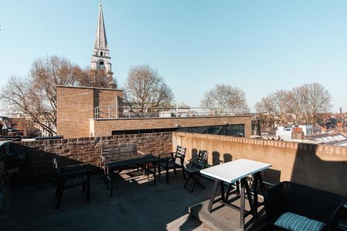 a rooftop patio with tables and chairs and a church at Private en-suite Room @ Liverpool street, Brick Ln in London